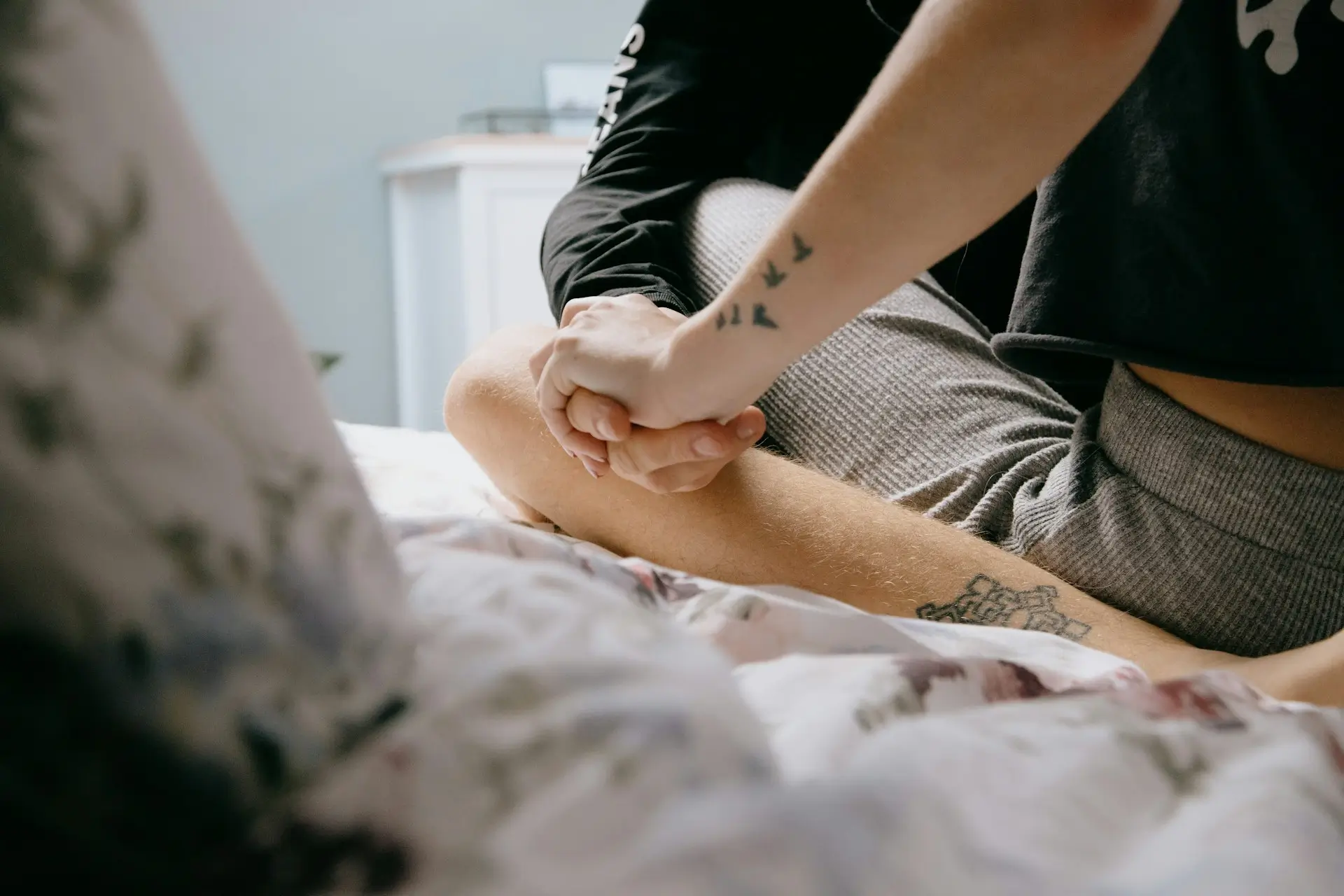 image of two people holding hands and sitting in each other's laps in bed